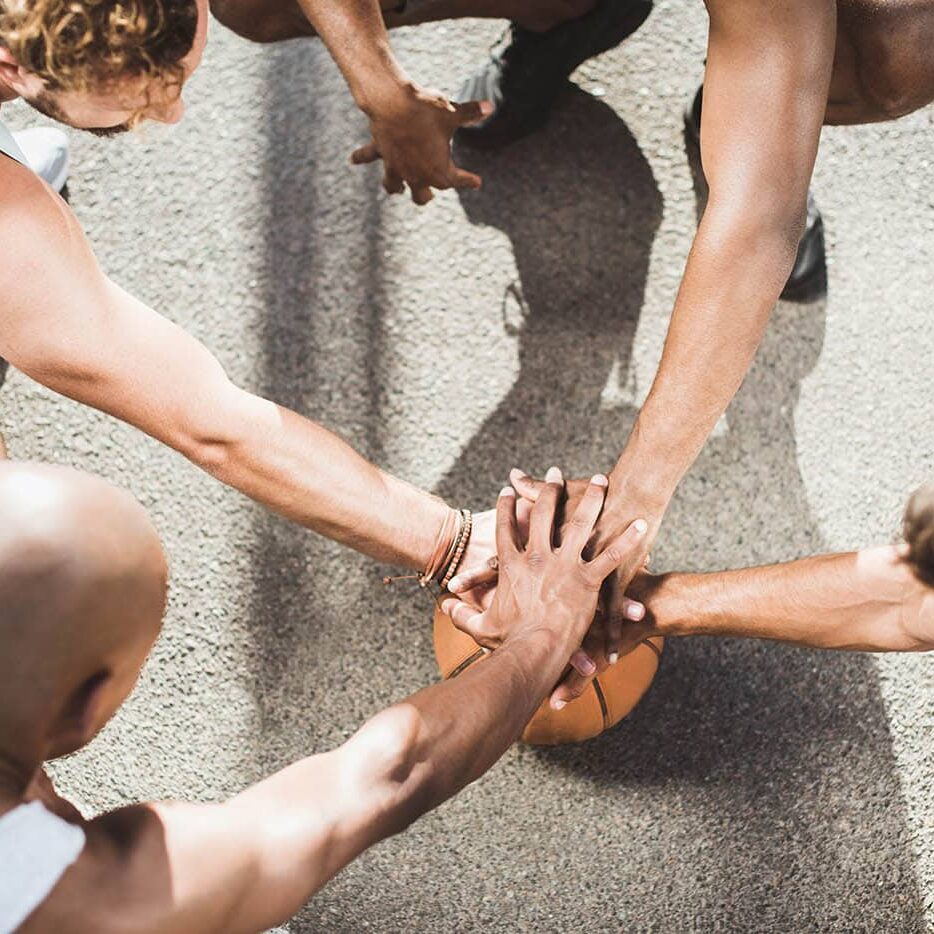Overhead View of Basketball Team Holding Hands on Basketball Bal