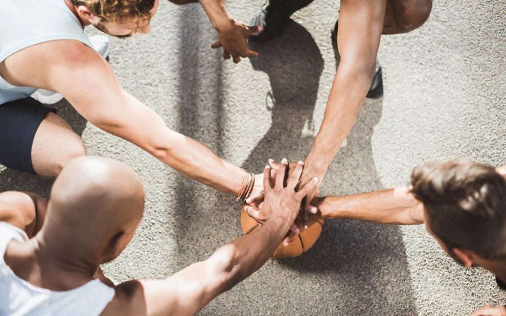 Overhead View of Basketball Team Holding Hands on Basketball Bal